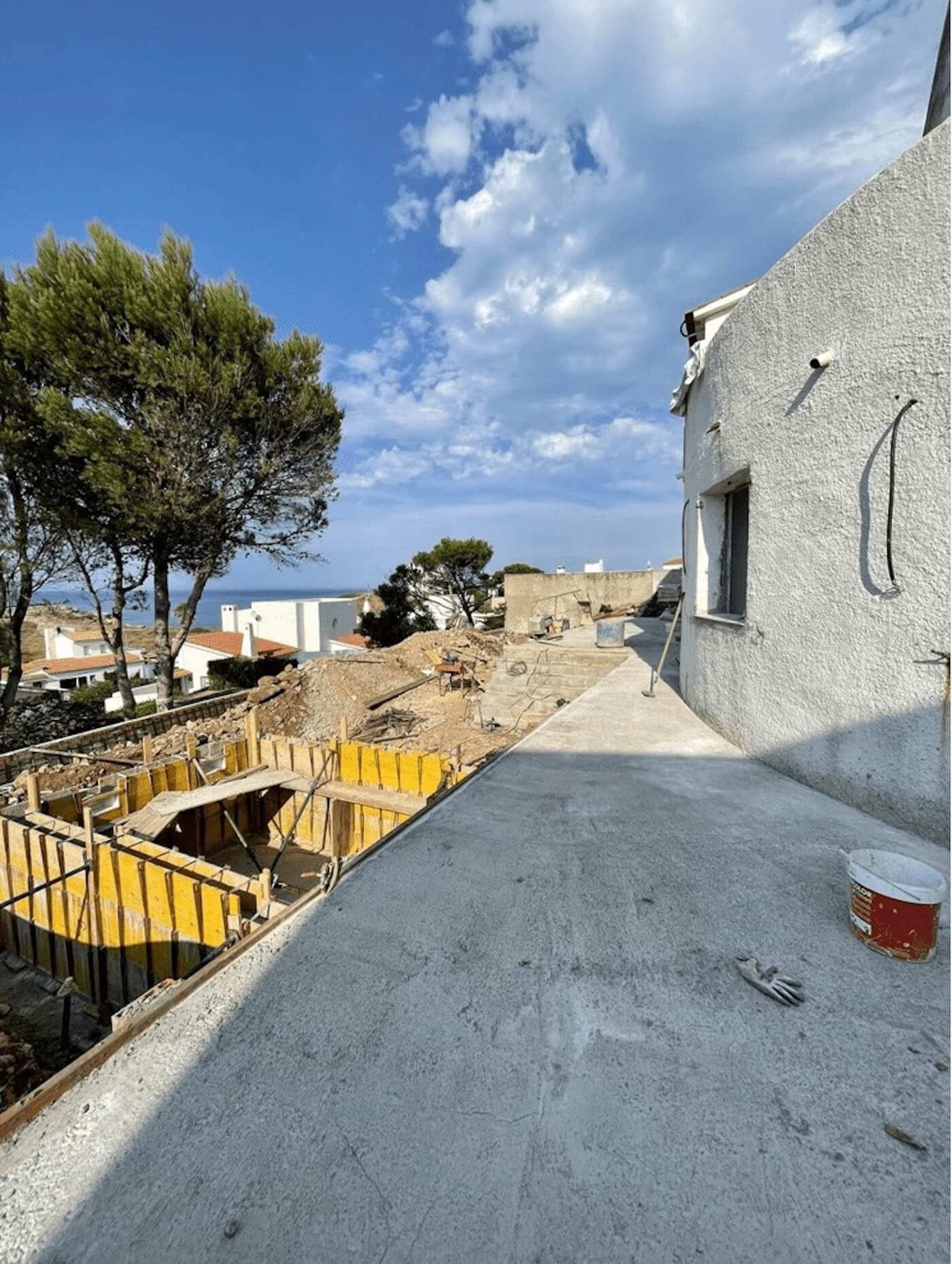 Estado previo a la reforma de una vivienda en la Costa Brava, con estructura en obra y vistas al mar.