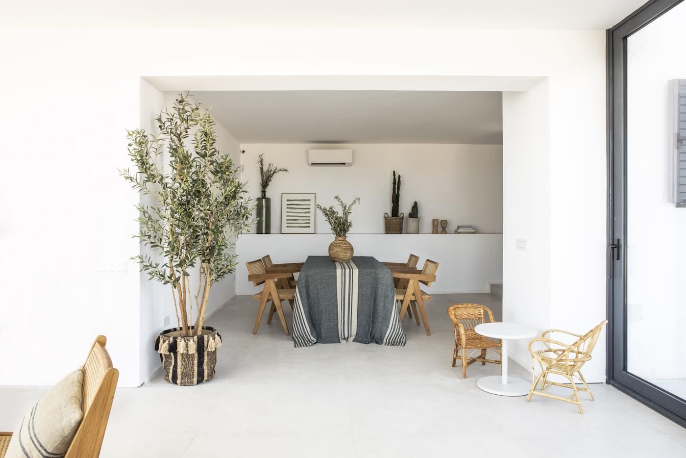 Comedor interior de casa mediterránea en la Costa Brava con mesa de madera, decoración natural y luz exterior.