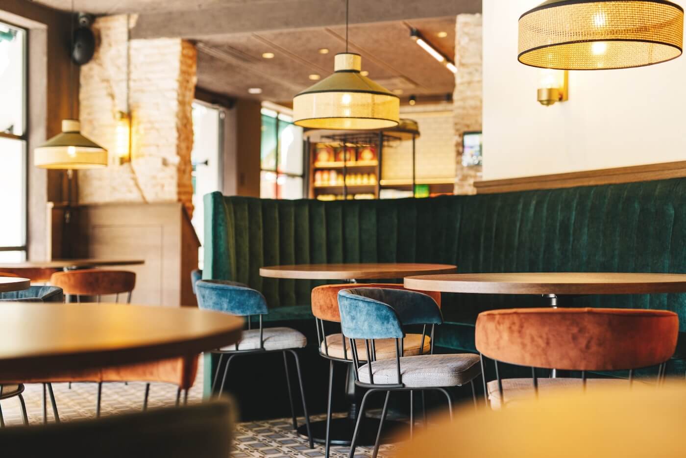 Zona de comedor del restaurante Casa Petra con mobiliario de diseño, iluminación cálida y bancos tapizados en verde.