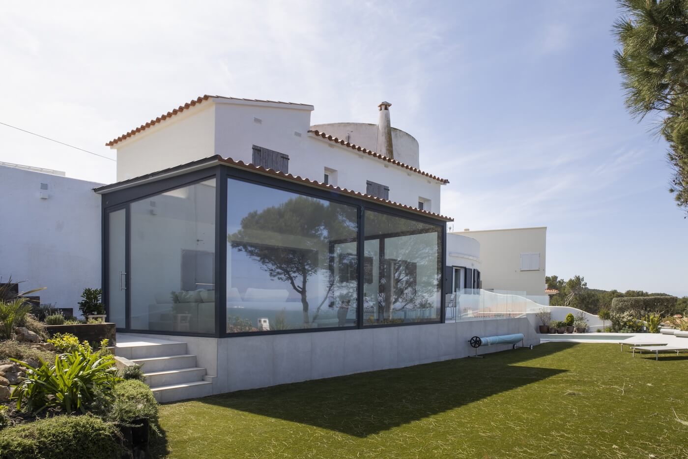 Fachada de vivienda mediterránea en la Costa Brava con porche acristalado diseñado por VBISOGNO.