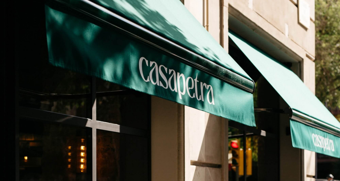 Toldo verde con el logotipo de Casa Petra en la fachada del restaurante en Barcelona.