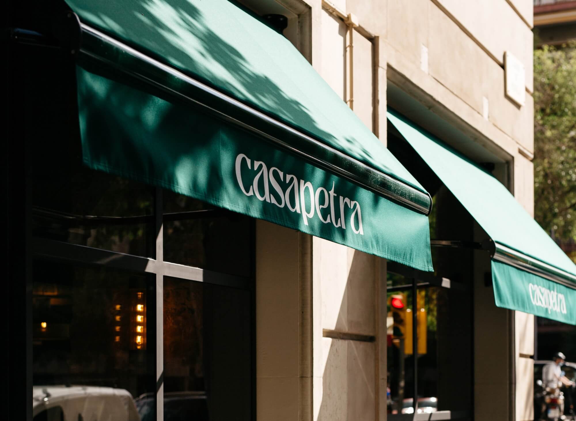 Toldo verde con el logotipo de Casa Petra en la fachada del restaurante en Barcelona.