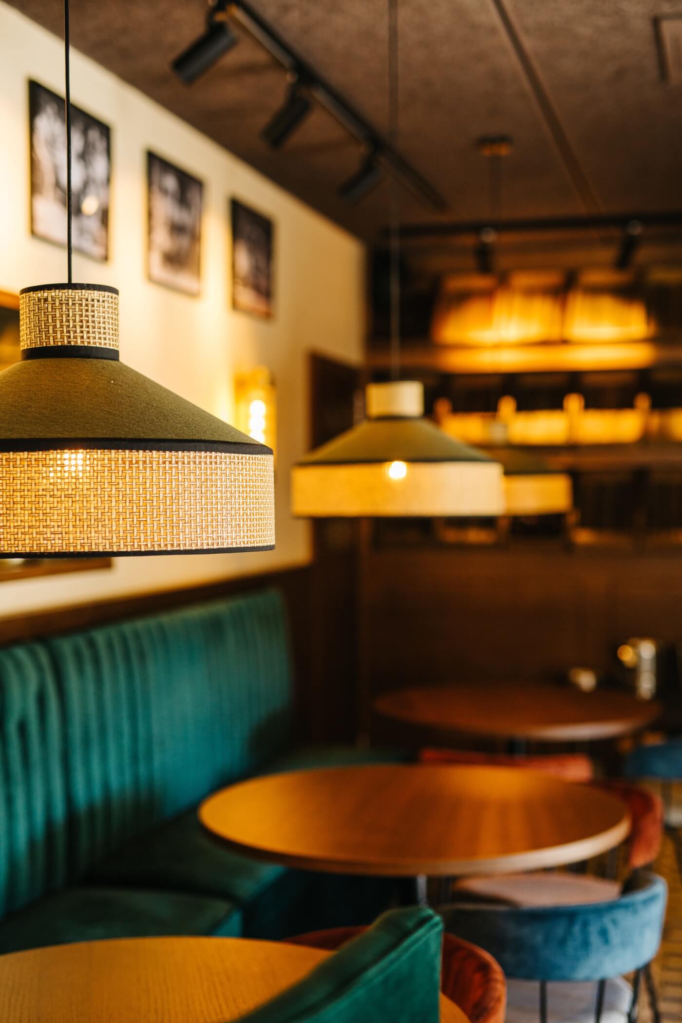 Lámparas suspendidas con diseño artesanal y mesas redondas de madera en el interior del restaurante Casa Petra en Barcelona.
