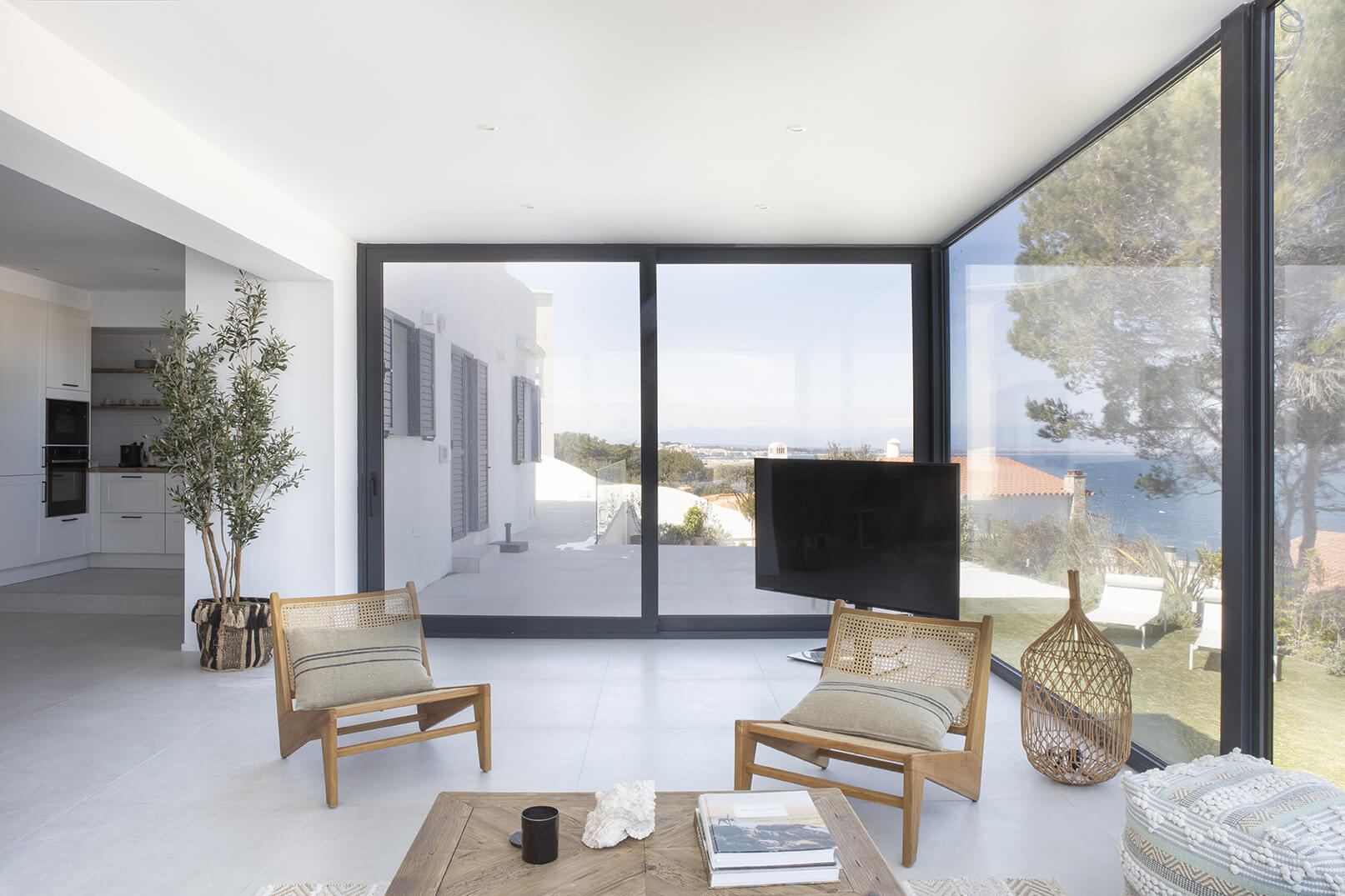 Sala de estar con grandes ventanales y vistas al mar en casa de la Costa Brava, con mobiliario de diseño y decoración natural.