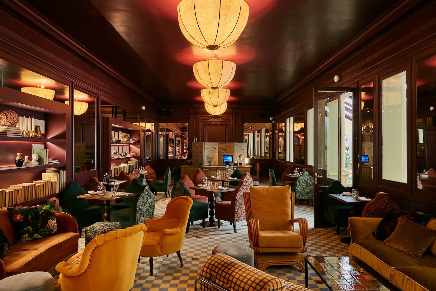 Salón del restaurante Gala con decoración de inspiración club, mobiliario vintage colorido e iluminación cálida.